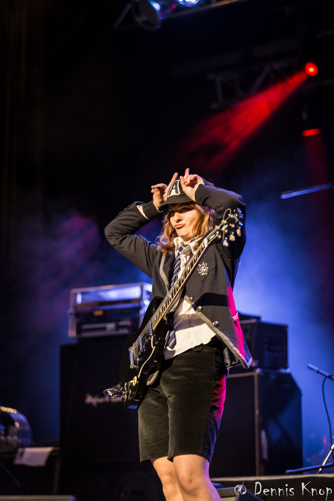 Weibliches Angus-Young-Double zeigt Hörner mit den Fingern, rot-blaues Licht, Bild Dennis Knop